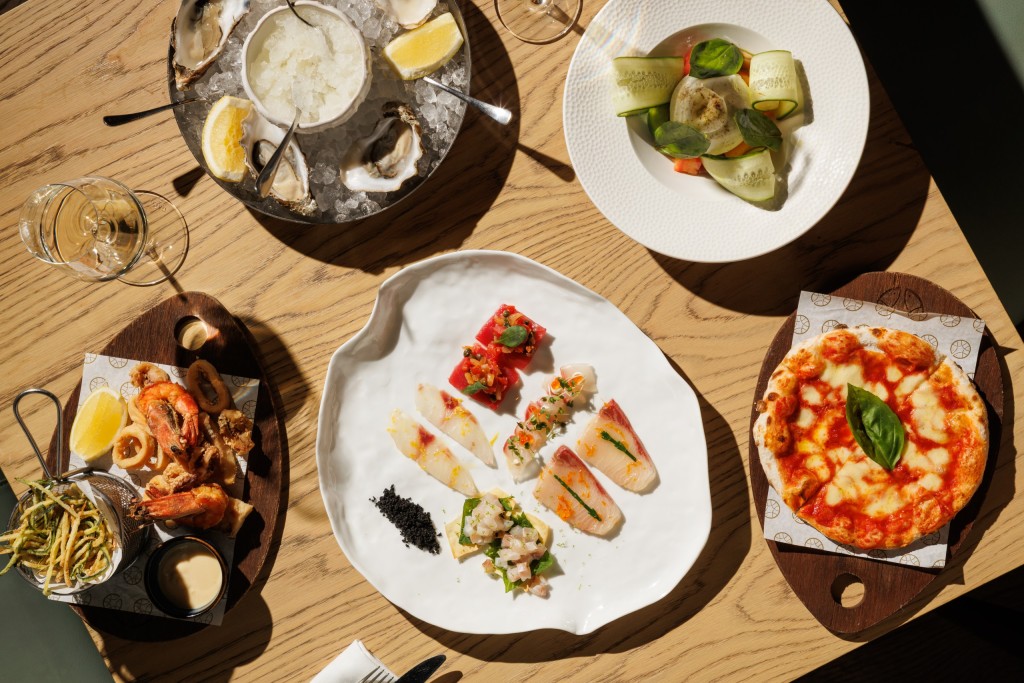 Mediterranean seafood dining at Azzurra Chelsea featuring oysters, calamari, crudo, Margherita pizza and fresh Italian coastal dishes served on a sunlit restaurant table in London.