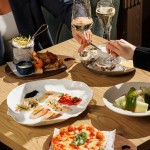 Guests enjoying a luxury Italian dining experience at Azzurra Chelsea, featuring seafood dishes, oysters, pizza and fine wine in an elegant Chelsea restaurant setting.