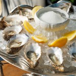 Fresh oysters served on crushed ice with lemon wedges at Azzurra Chelsea, an Italian seafood restaurant in Chelsea, London.