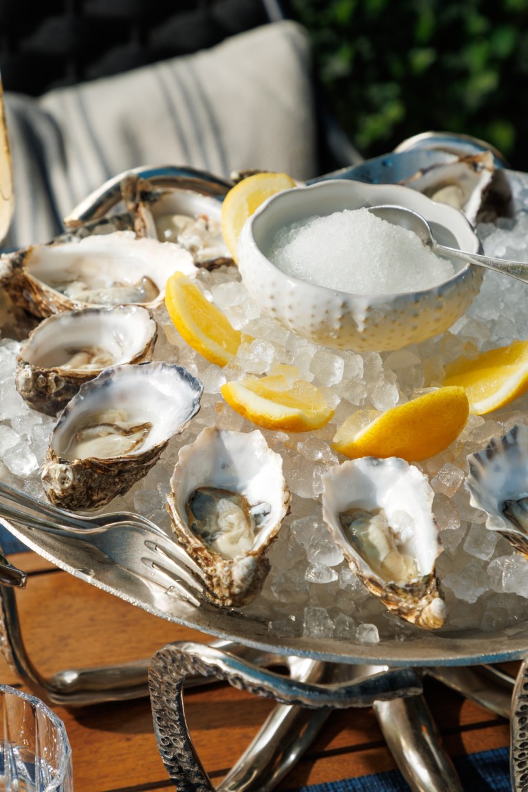 Fresh oysters served on crushed ice with lemon wedges at Azzurra Chelsea, an Italian seafood restaurant in Chelsea, London.