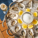 Fresh oysters served on crushed ice with lemon wedges and champagne at Azzurra Chelsea, an Italian seafood restaurant in Chelsea, London.