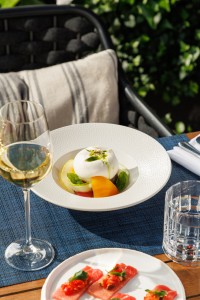 Creamy burrata with heritage tomatoes, basil and olive oil served al fresco at Azzurra Chelsea, an authentic Italian restaurant in Chelsea, London.