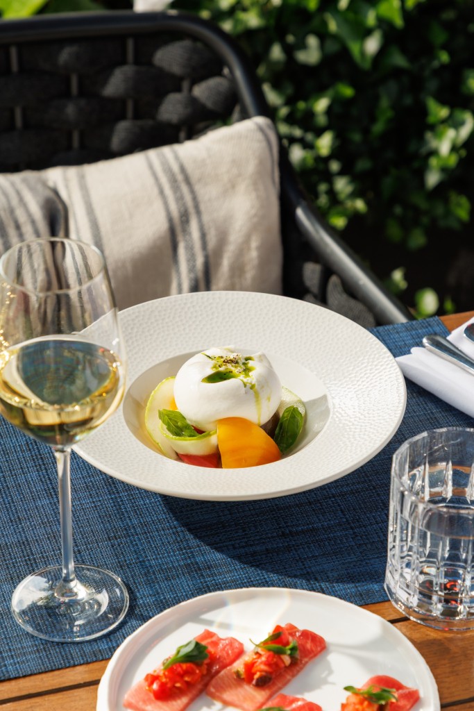 Creamy burrata with heritage tomatoes, basil and olive oil served al fresco at Azzurra Chelsea, an authentic Italian restaurant in Chelsea, London.